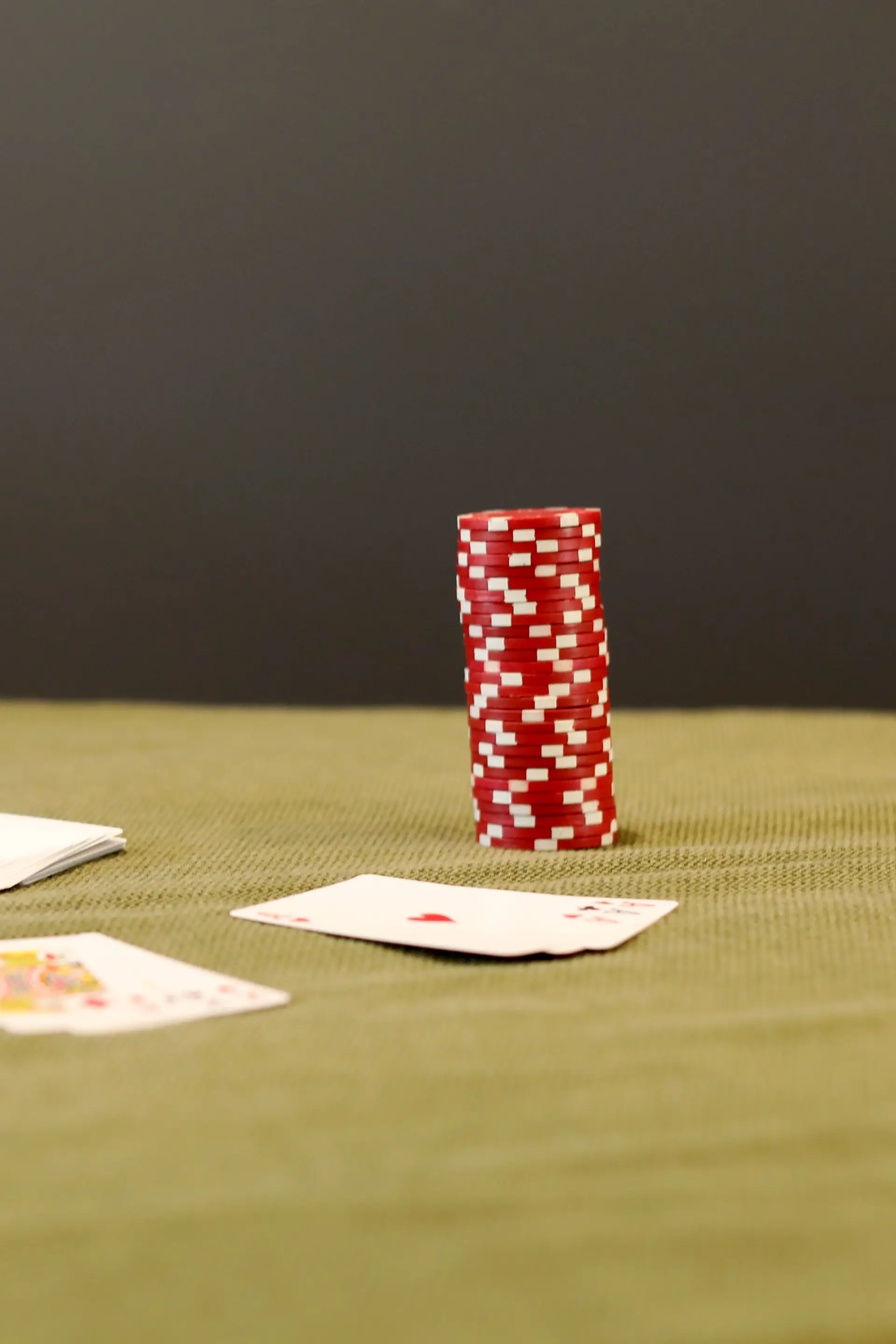Punaiset pokerimerkit ja pelikortit vihreällä huovalla